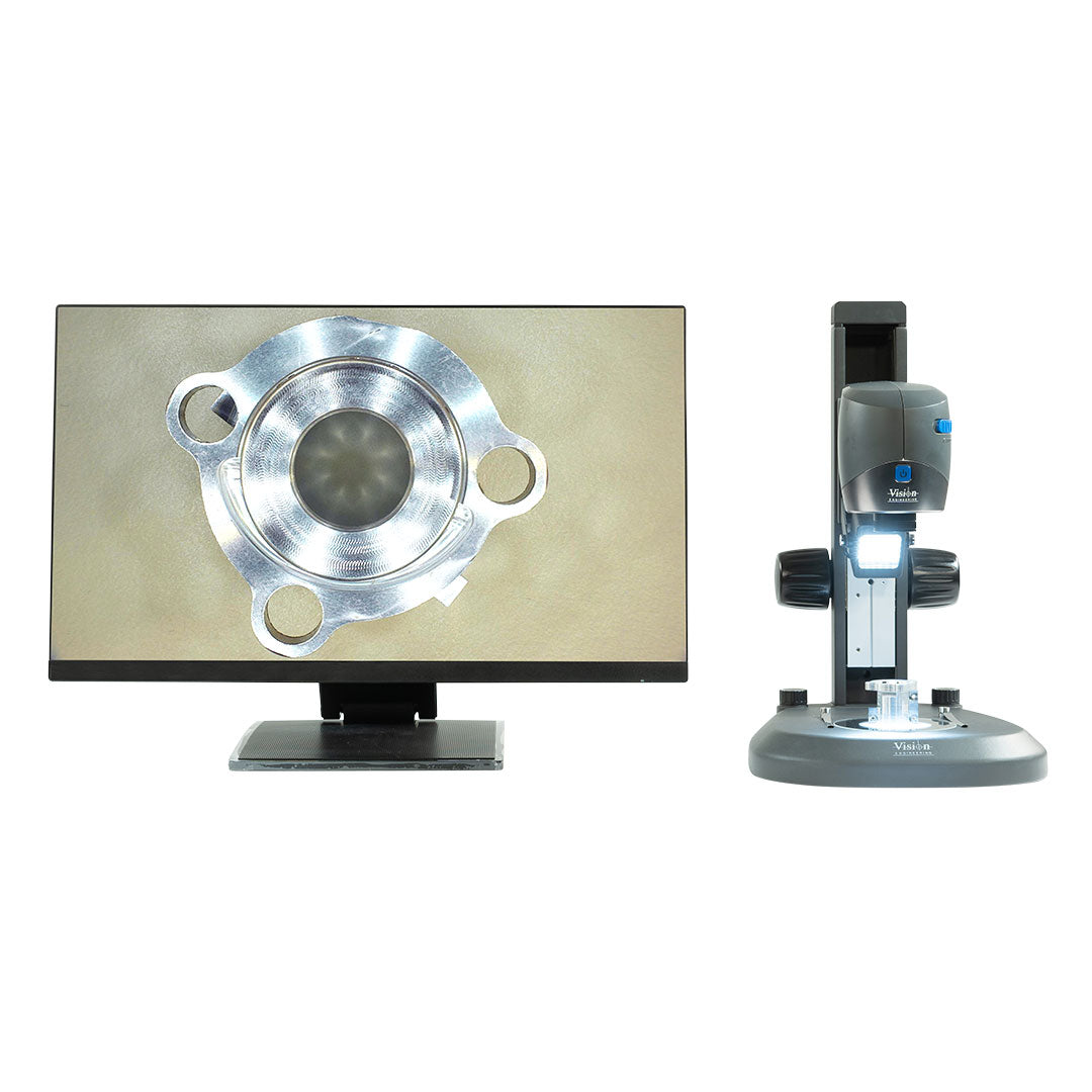 Digital microscope with a silver cylindrical component on stage, adjustable bench stand, and a 24-inch monitor.